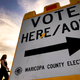 Voters deliver their ballot to a polling station in Tempe, Ariz., on Nov. 3, 2020. The U.S. Department of Justice on Tuesday, July 5, 2022, sued Arizona over a new law requiring people who use a federal form to register to vote to provide additional proof of citizenship if they want to vote for president or using the state’s popular vote-by-mail system.